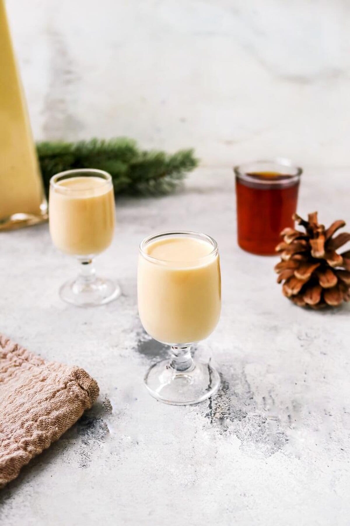 Jemand gießt cremigen, hellen Likör in ein Glas, daneben eine zweite Flasche Likör – Foto: Sandra Leibinger