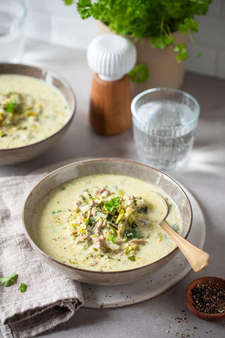 Zwei Hände halten einen Teller mit heller Suppe, garniert mit Kräutern – Foto: Anna Gieseler