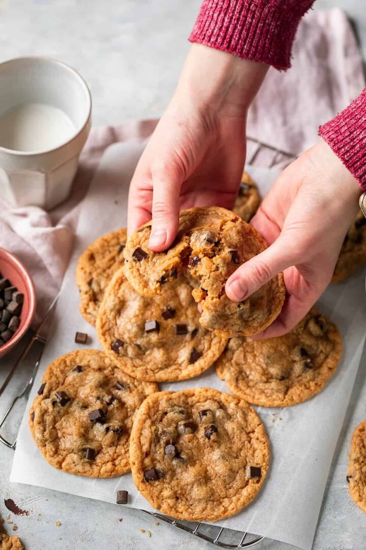 Zwei Hände halten einen Keks mit Chocolate Chips und brechen ihn auseinander