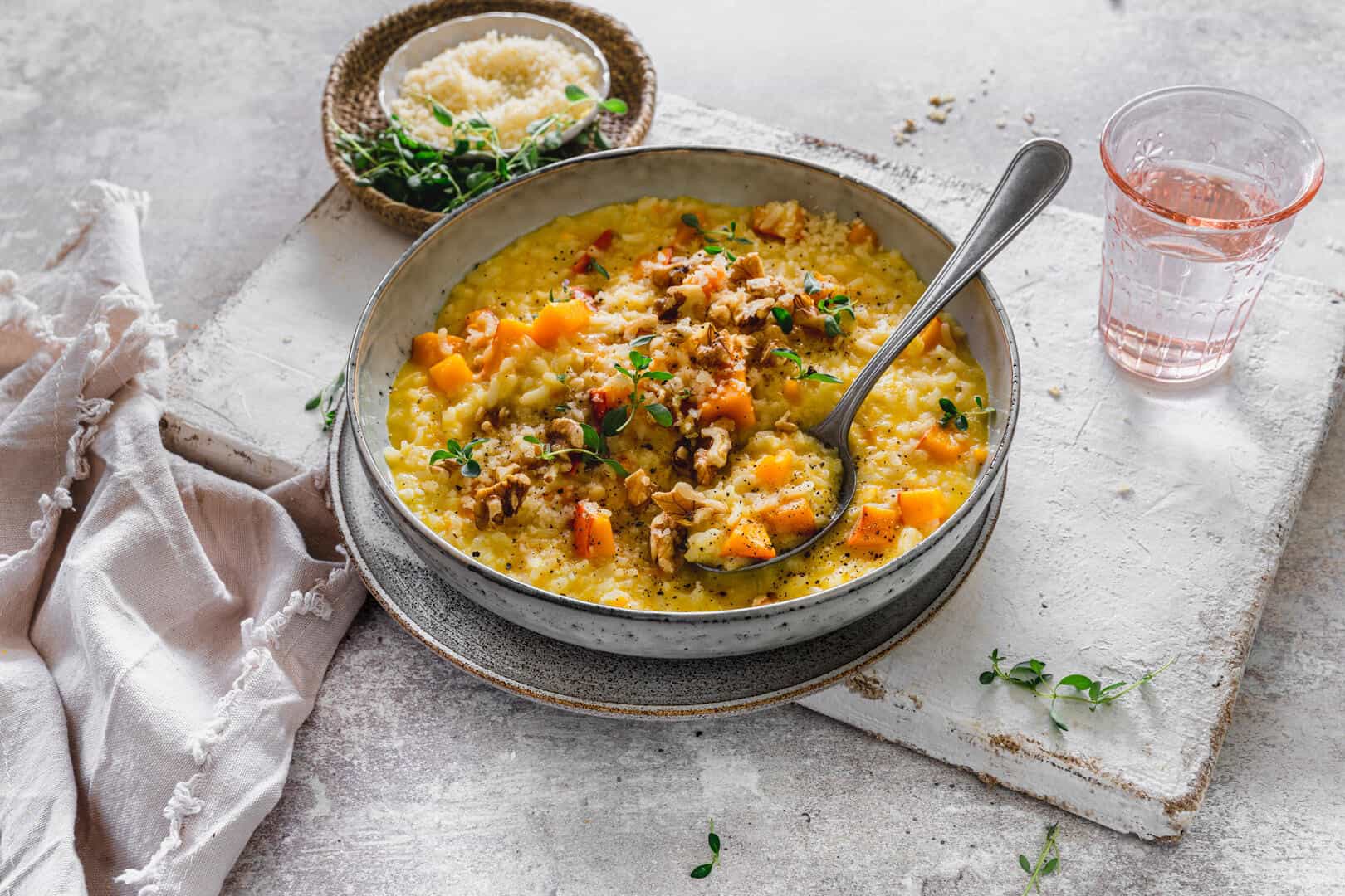 Kürbisrisotto auf einem grauen Teller, mit gehackten Nüssen garniert – Foto: Tina Bumann