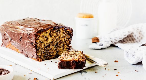 Heller Kastenkuchen mit Schokostückchen und Glasur, angeschnitten auf hellem Untergrund – Foto: Désirée Peikert