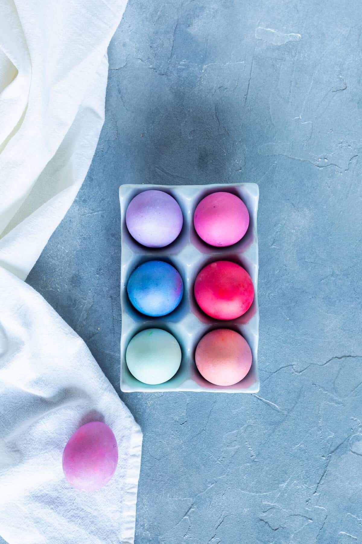 Gefärbte Eier in einem Karton von oben fotografiert auf grau-blauem Untergrund – Foto: Kathrin Knoll