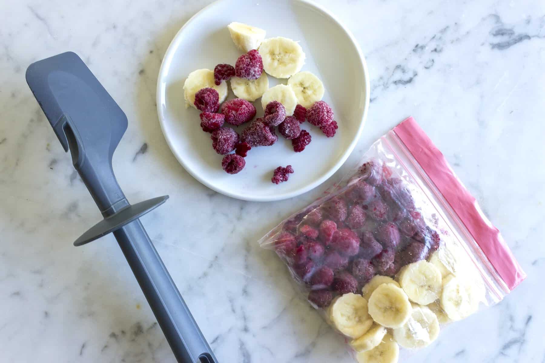 gefrorene Bananenstücke und Himbeeren in einem Gefrierbeutel
