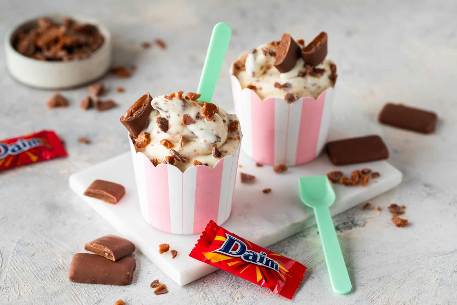 McFlurry Eis mit Daim, zwei Becher, daneben liegt ein Daim und ein Löffel
