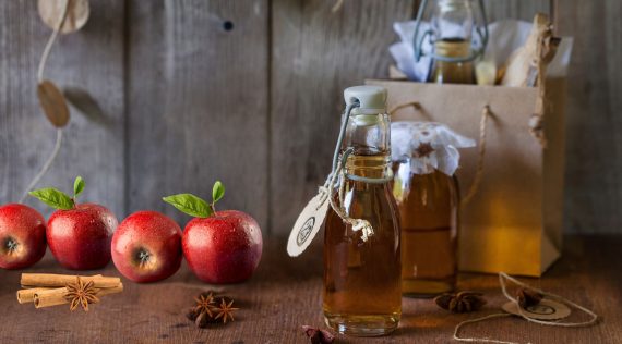 Bratapfellikör in Flaschen, daneben Äpfel – Foto: Frauke Antholz