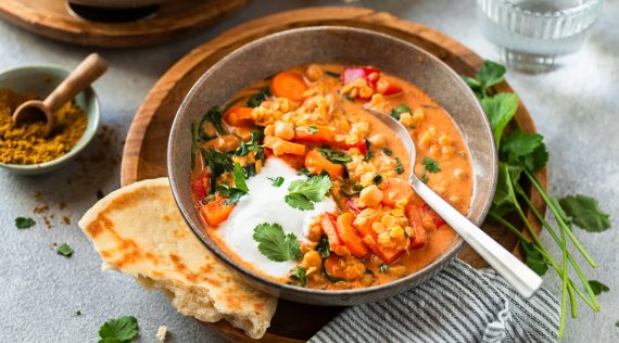 Linsencurry in einer grauen Schale, daneben ein Stück Brot – Foto: Anna Gieseler
