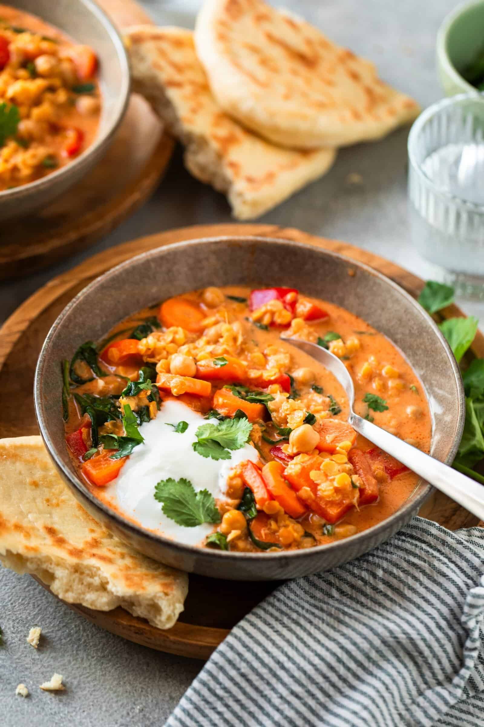 Linsencurry in einer grauen Schale, daneben ein Stück Brot – Foto: Anna Gieseler