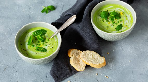 Zwei Schalen mit Erbsensuppe auf grauem Untergrund, mit Minzblättern garniert – Foto: Kathrin Knoll
