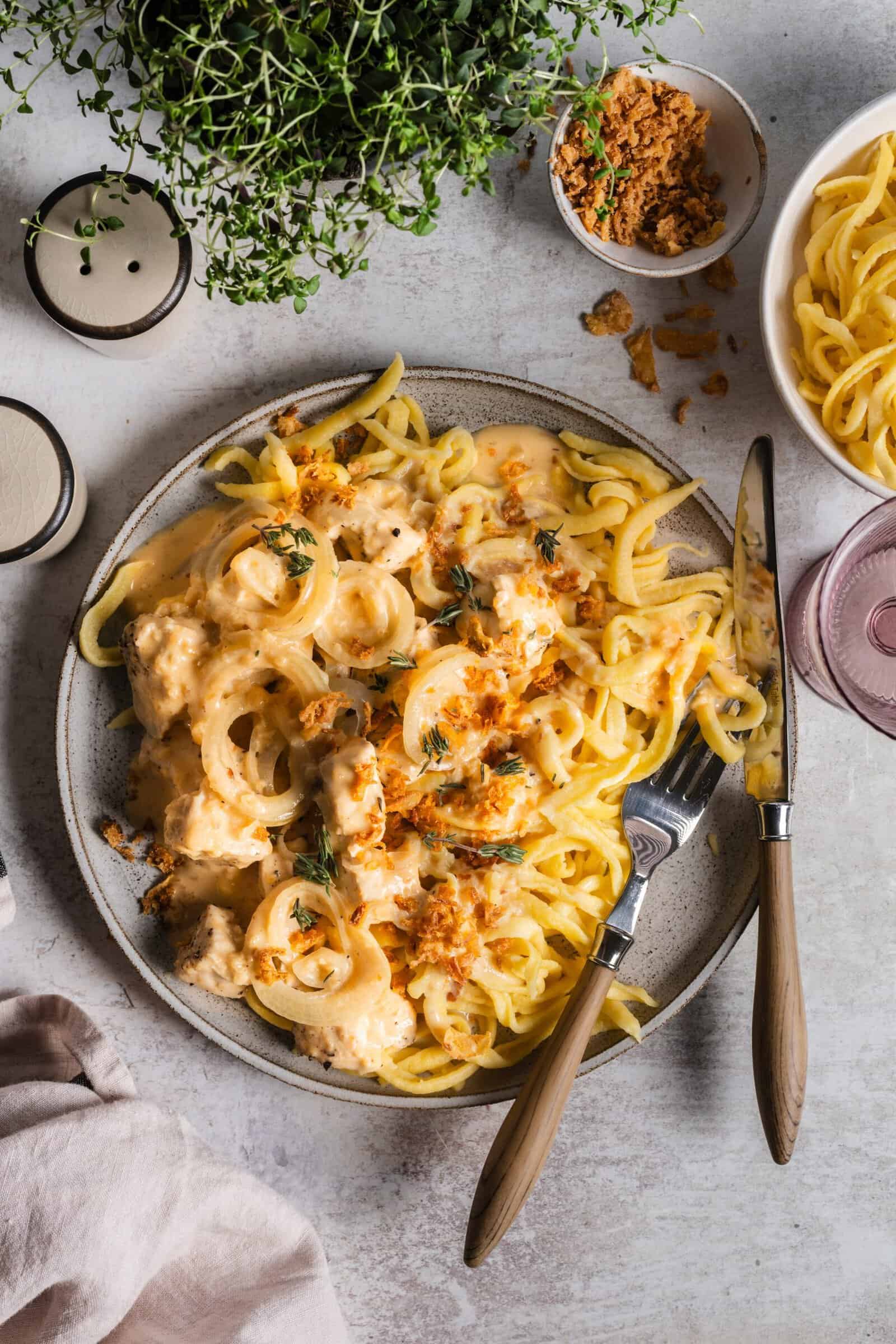 Ein grauer Teller von oben fotografiert, darauf Spätzle, Soße, Fleisch