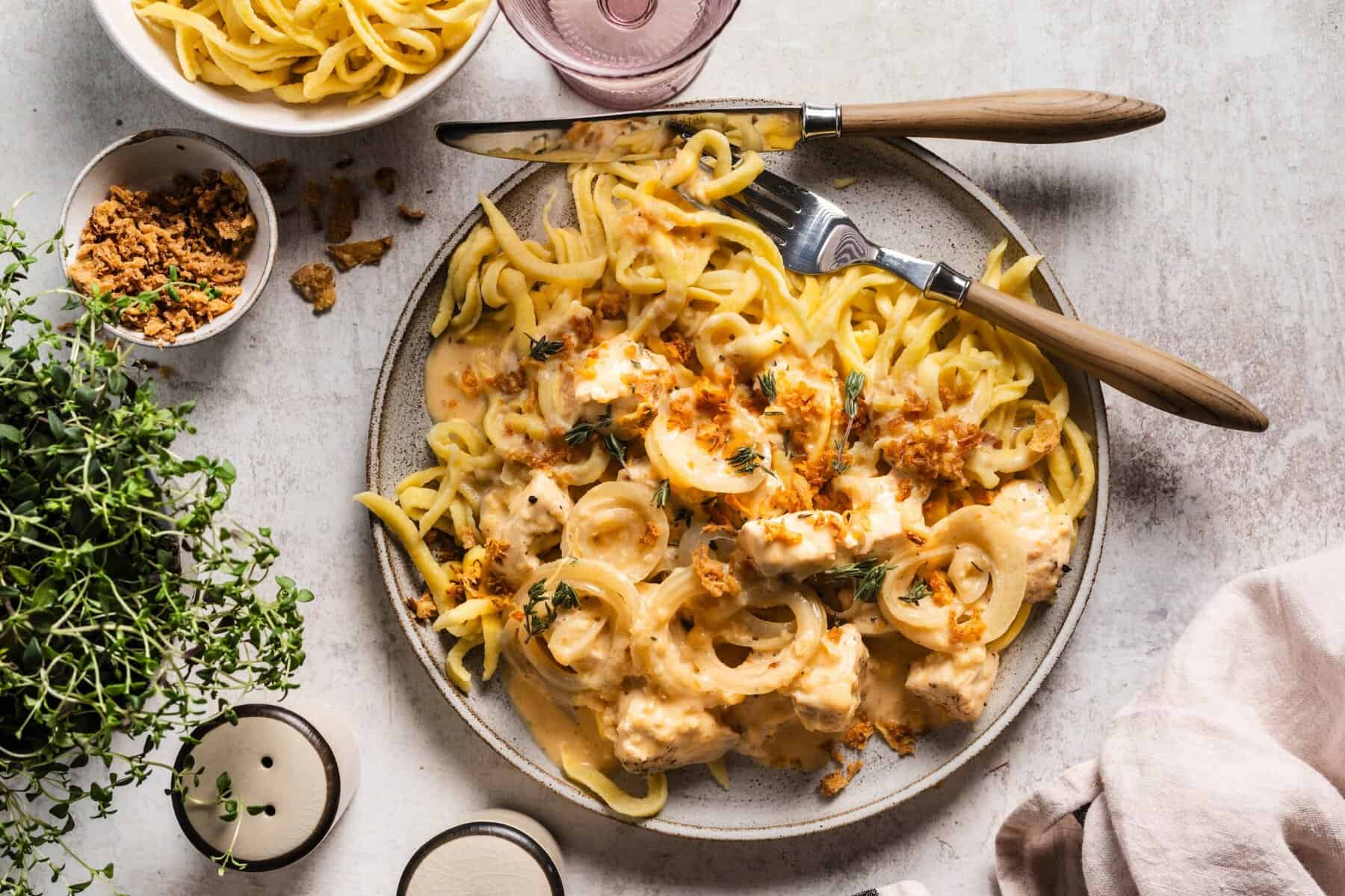 Ein grauer Teller von oben fotografiert, darauf Spätzle, Soße, Fleisch