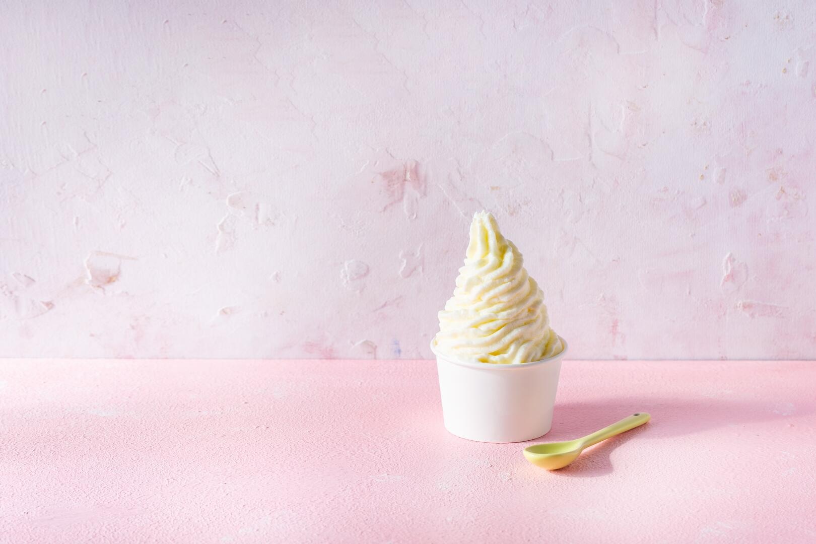 Frozen Joghurt in einem weißen Becher vor rosa Hintergrund
