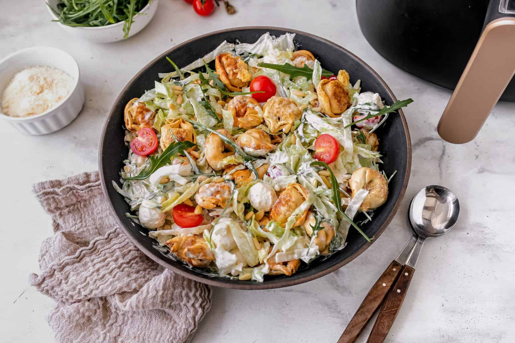 Eine Pfanne mit einem bunten Salat von oben fotografiert, Tomaten, Tortellini, Eisbergsalat