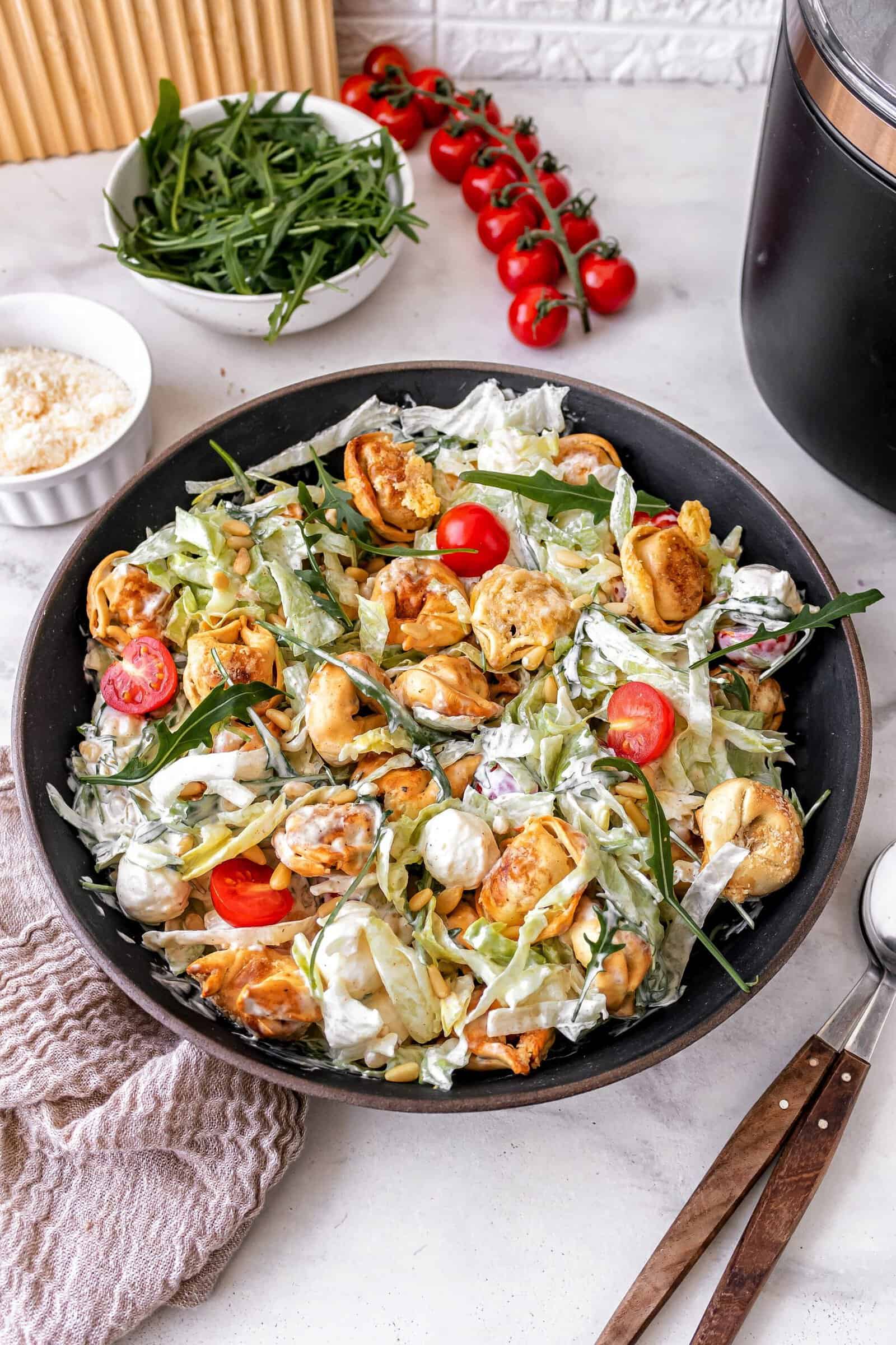 Eine Pfanne mit einem bunten Salat von oben fotografiert, Tomaten, Tortellini, Eisbergsalat