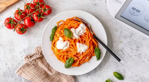 Ein weißer Teller mit Spaghetti, garniert mit Burrata von oben fotografiert