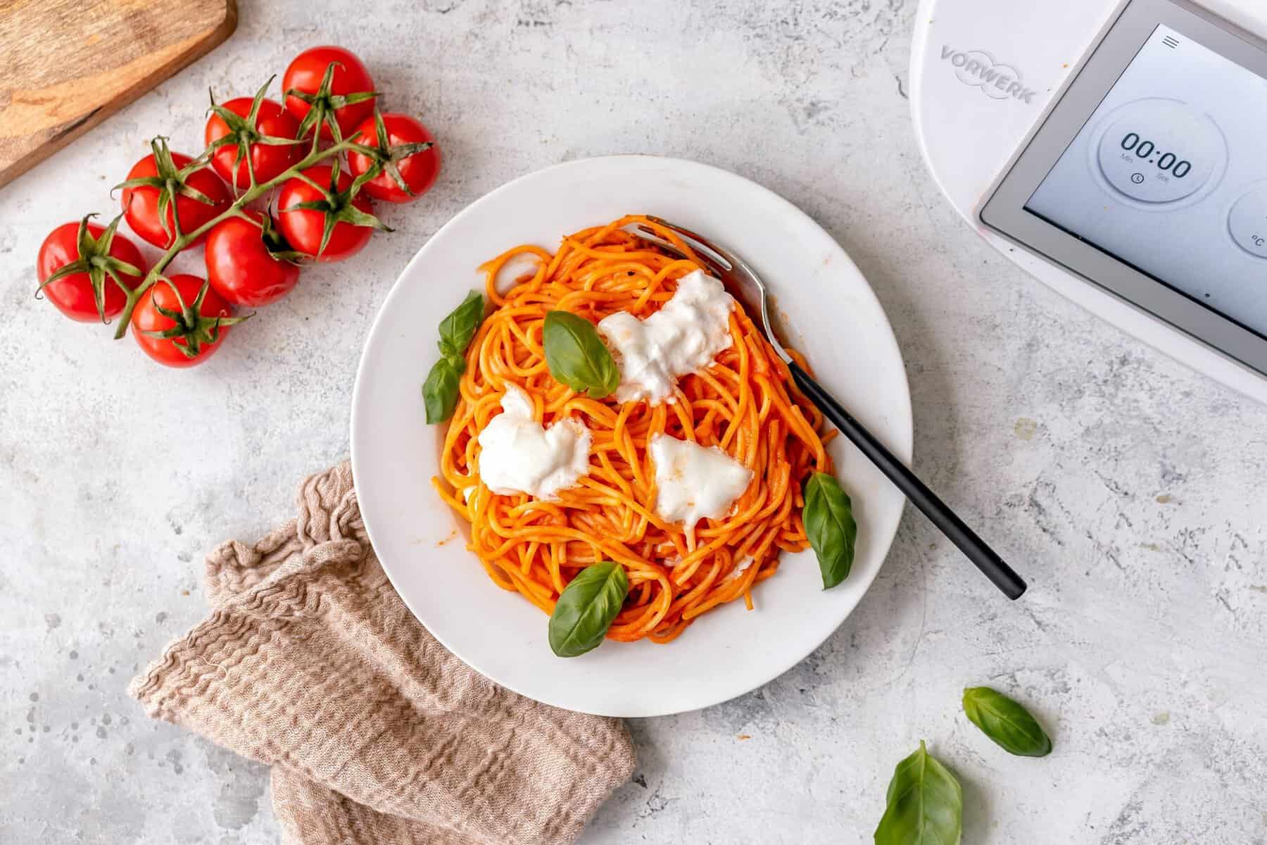 Ein weißer Teller mit Spaghetti, garniert mit Burrata von oben fotografiert
