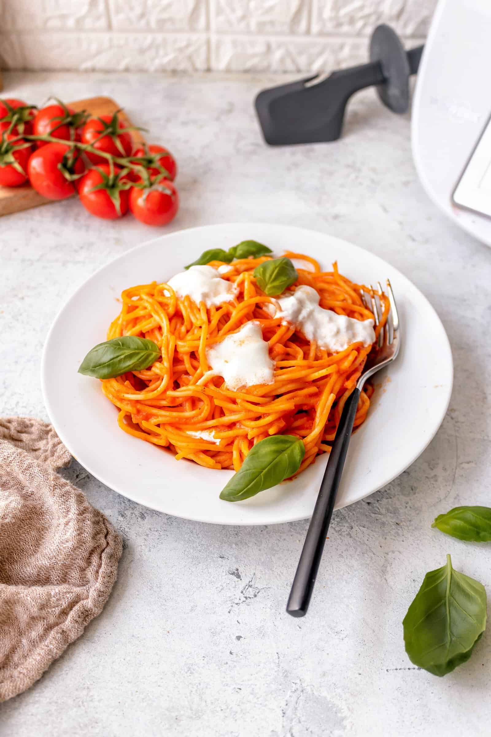 Ein weißer Teller mit Spaghetti, garniert mit Burrata von oben fotografiert