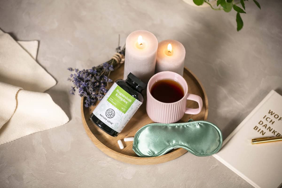 ein kleines Tablett mit einer Tasse Tee, Kerzen und einem Magnesium-Produkt